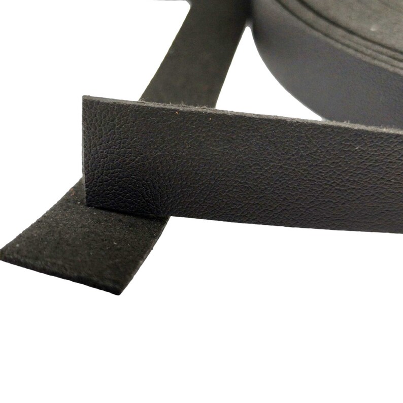 K&ouml;nnte beinhalten: Schwarzes Lederband mit strukturierter Oberfl&auml;che. Das Band ist aufgerollt und &uuml;ber sich selbst gefaltet.
