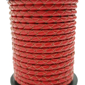 Peut inclure: Un gros plan d'une bobine de cordon en cuir tressé rouge. Le cordon est tissé en forme de losange et est parfait pour les projets d'artisanat.