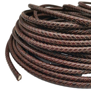May include: A close-up of a brown leather cord, braided in a diamond pattern. The cord is coiled and ready for use in crafting projects.