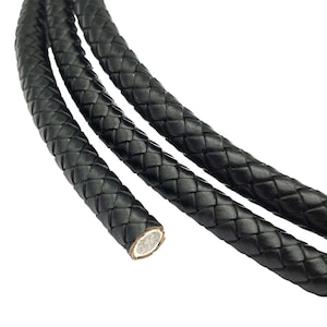Könnte beinhalten: Nahaufnahme eines schwarzen geflochtenen Lederkordels. Das Kordel ist in einem Rautenmuster gewebt und hat eine glatte, polierte Oberfläche.
