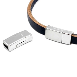 Pode incluir: Fecho magnético prateado para pulseiras de couro. O fecho é feito de duas peças que se encaixam.