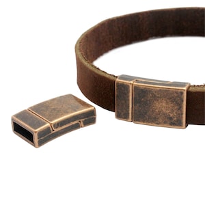 Puede incluir: Un par de cierres magnéticos de cobre antiguo para pulseras de cuero. Los cierres son rectangulares y tienen un acabado desgastado.