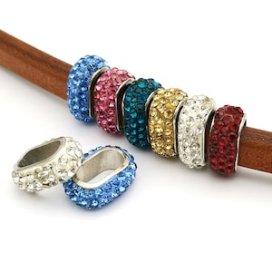 May include: Assortment of colorful rhinestone charm beads for jewelry making. The beads are silver-toned and feature a variety of colors, including blue, pink, teal, gold, white, and red.
