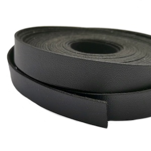 K&ouml;nnte beinhalten: Eine Rolle schwarzes Lederband, etwa 1,2 cm breit, ist auf einem wei&szlig;en Hintergrund aufgerollt.