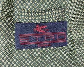 May include: A green tie with a small white circle pattern. The tie has a navy blue label with a red bird logo and the text "ETRO Milano".