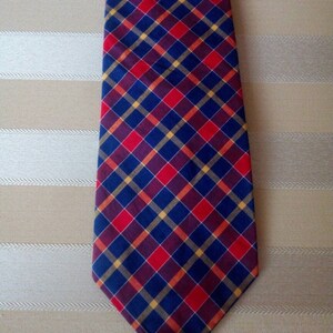 May include: A navy blue tie with a red, yellow, and burgundy plaid pattern.