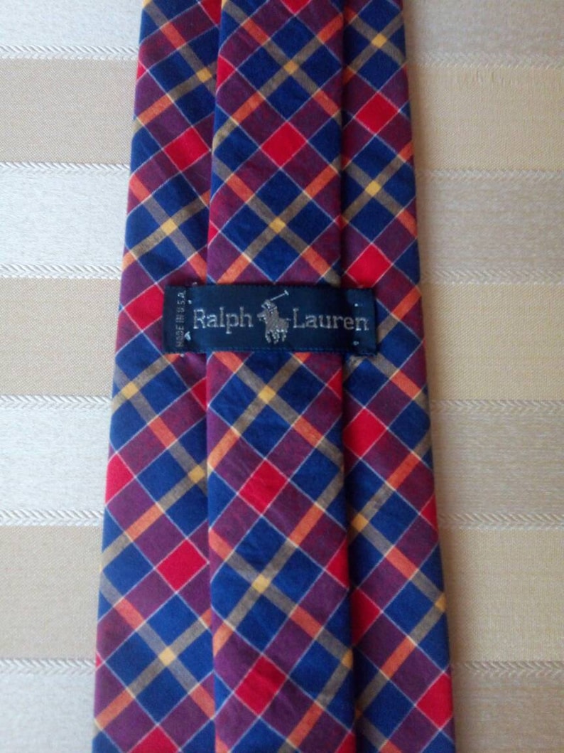 May include: A red, blue, and yellow plaid tie with a black label that reads "Ralph Lauren".
