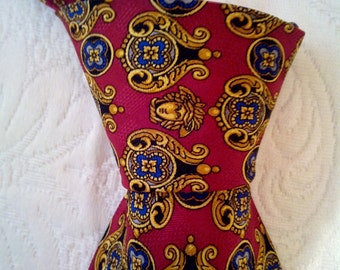 May include: A red silk tie with a gold and blue paisley pattern. The pattern features a repeating design of stylized flowers and leaves.