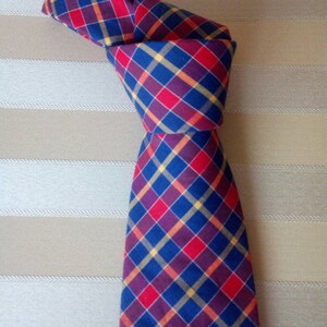 May include: A blue, red, and yellow plaid tie with a knot tied at the top.