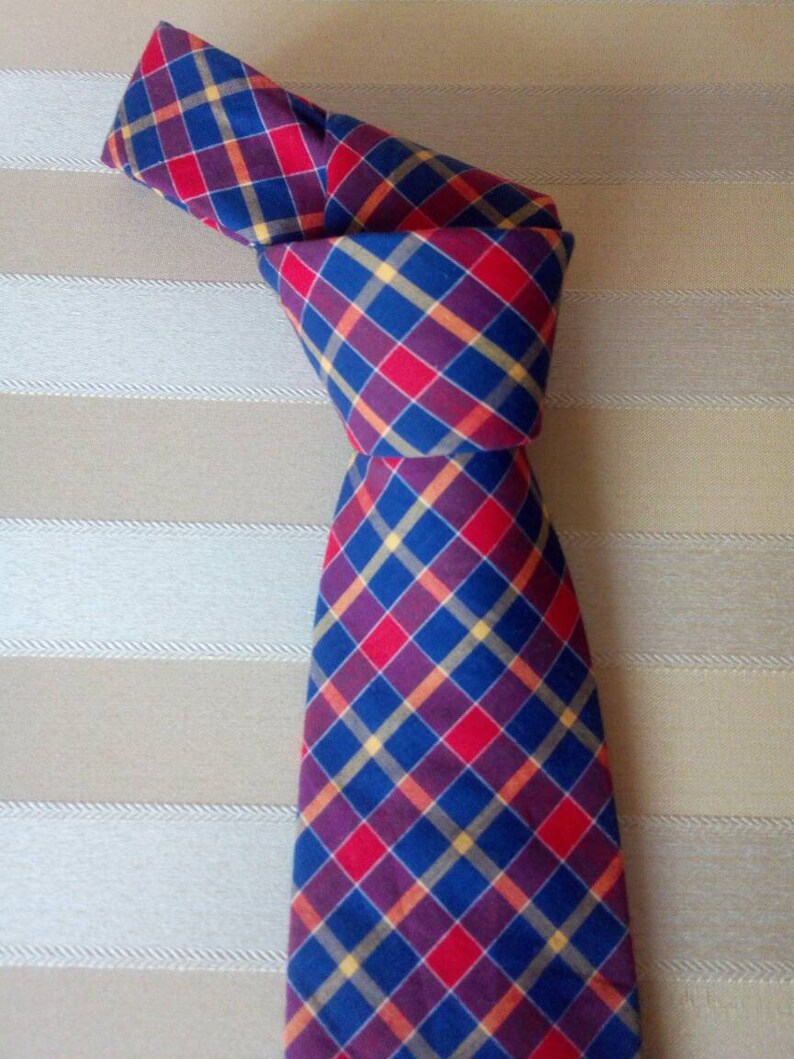 May include: A blue, red, and yellow plaid tie with a knot tied at the top.
