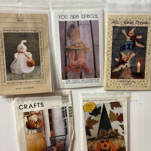 Op de afbeelding: Een verzameling Halloween-thema knutselpatronen, waaronder een sneeuwpop, vogelverschrikker en pompoen. De patronen tonen verschillende ontwerpen en de teksten "BOO" en "YOU ARE SPECIAL". De patronen zitten in plastic hoezen.