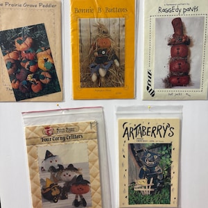 May include: Five craft pattern packets in plastic sleeves. The packets feature images of pumpkins, scarecrows, and other fall-themed characters. Titles include "The Prairie Grove Peddler," "Bonnie B Buttons," and "Raggedy Pants."