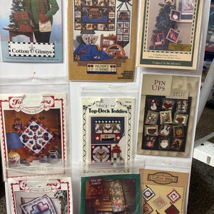 Op de afbeelding: Een verzameling knutselpatroonpakketten, met ontwerpen voor zak sjaals, de Ark van Noach, kerstversieringen en volkskunst. De pakketten bevatten verschillende thema's en ontwerpen, met afbeeldingen van voltooide projecten en instructies.