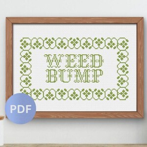 May include: A cross-stitch pattern framed in wood featuring the text WEED BUMP in green thread. The design is enclosed within a decorative green floral border on a white fabric background. A blue circular icon with the white text PDF is visible.