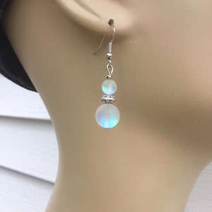May include: Silver dangle earrings with two iridescent white glass beads.