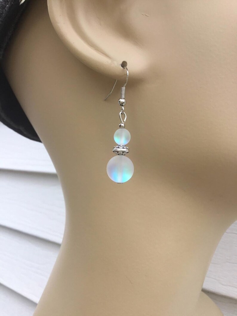 May include: Silver dangle earrings with two iridescent white glass beads.