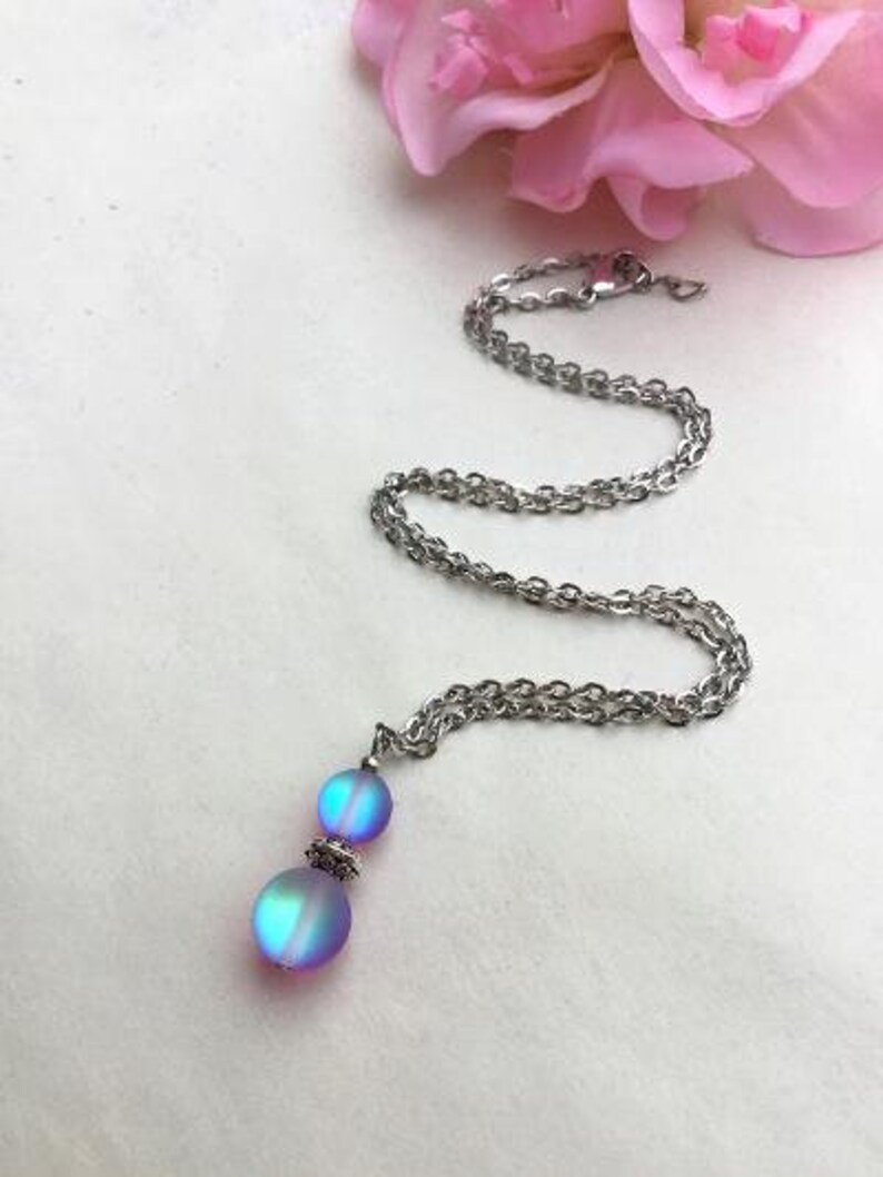 May include: A silver chain necklace with a iridescent blue and purple pendant featuring two round beads.