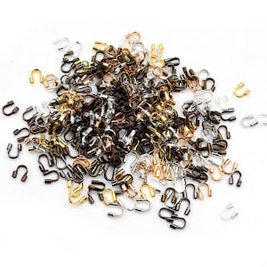 May include: A large assortment of small, metal,  U-shaped clasps in gold, silver, and bronze tones. The clasps are used for jewelry making and crafting.