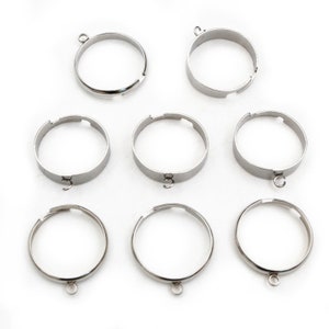 Könnte beinhalten: Neun silberfarbene Metallringe mit einer kleinen Schlaufe an der Seite. Die Ringe sind dafür ausgelegt, einen Anhänger oder einen Glücksbringer zu halten.