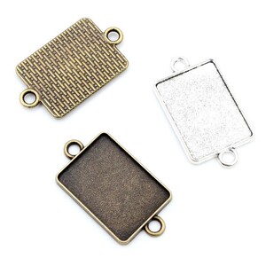 May include: Three rectangular metal pendant trays with two jump rings on each side. One tray is antique gold with a textured surface, and the other two are plain, one in antique silver and one in antique gold.