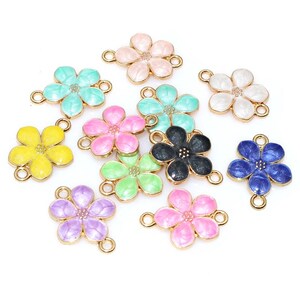 Op de afbeelding: Een verzameling kleurrijke bloemvormige bedels. De bedels zijn in verschillende kleuren, waaronder geel, roze, blauw, groen en zwart, met goudkleurige lussen om aan sieraden of andere knutselwerken te bevestigen. De bloemen hebben een glanzende afwerking.