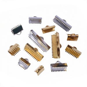 May include: A collection of metal ribbon crimp ends in silver and gold tones. Each piece features a U-shaped channel with internal teeth for gripping fabric or ribbon, and a small loop at the top for attaching jewellery findings or connectors.
