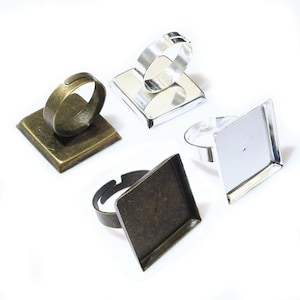 Puede incluir: Cuatro bases de anillo de plata y bronce con engastes cuadrados para hacer joyas personalizadas. Los engastes están vacíos y listos para ser rellenados con resina, vidrio u otros materiales.