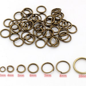 Peut inclure: Un tas de anneaux de saut dorés de différentes tailles, allant de 3 mm à 10 mm. Les anneaux sont disposés par ordre de taille, du plus petit au plus grand.