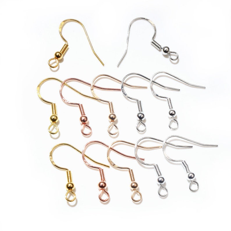 May include: A set of 12 earring hooks in gold, silver, and rose gold. The hooks are made of metal and have a small ball at the end.