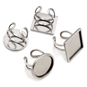 Puede incluir: Cuatro bases de anillo de plata con biseles de diferentes formas. Los biseles son redondos, cuadrados y rectangulares. Los anillos son de metal y están listos para ser personalizados.