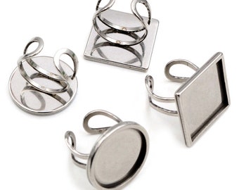 May include: Four silver ring blanks with different shaped bezels. The bezels are round, square, and rectangular. The rings are made of metal and are ready to be customized.