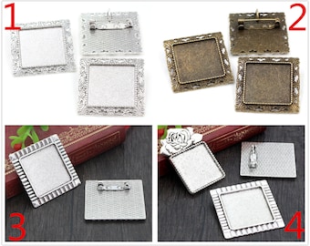 Puede incluir: Cuatro marcos metálicos cuadrados de color plateado y bronce con un centro en blanco para agregar una foto o un diseño. Los marcos tienen un borde decorativo y un broche de seguridad para sujetar a la ropa o a un bolso.