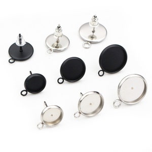 Peut inclure: Huit montures de boucles d'oreilles argentées avec des cabochons en verre noir et transparent. Les montures ont une boucle pour attacher un charme ou un pendentif.