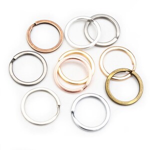 May include: Assortment of eight key rings in different metal finishes, including silver, gold, bronze, and rose gold. The key rings are all circular and have a smooth finish.