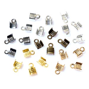 May include: Assortment of metal cord end caps in gold, silver, and black finishes. The caps have a small loop at the top for attaching to a cord or string.