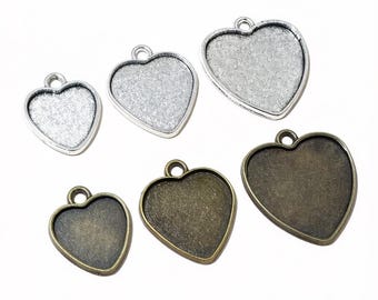 Puede incluir: Una colección de bandejas colgantes en forma de corazón en varios tamaños y acabados. Las bandejas son en tonos plateados y bronce, con un lazo en la parte superior para sujetar a una cadena o cordón. Ideales para la fabricación de joyas y manualidades.