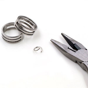 May include: Two silver jump rings and a pair of silver pliers on a white surface.