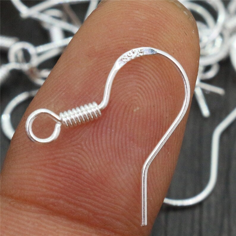 May include: Silver earring hooks with a spring-loaded closure. The hooks are made of metal and have a shiny finish.