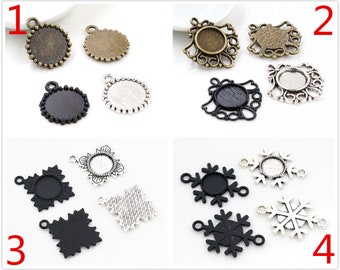 May include: Assortment of 10 silver and black metal pendant trays with different designs, including round, ornate, and snowflake shapes. The trays are designed to hold small round glass cabochons for jewellery making.