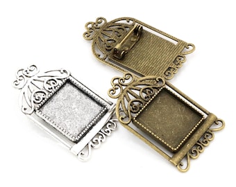 Puede incluir: Dos marcos de metal plateado y bronce con una abertura cuadrada para un camafeo u otro adorno. Los marcos tienen un diseño de filigrana decorativo y un broche.