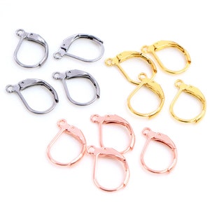 Peut inclure: Divers modèles de fermoirs de boucles d'oreilles de type dormeuse en argent, or et or rose. Les fermoirs sont présentés sur un fond blanc, mettant en valeur leurs différentes finitions métalliques et leurs designs. Ces composants sont utilisés pour la fabrication de bijoux.