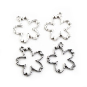 May include: Four silver and black metal flower-shaped charms with a loop at the top for attaching to jewelry or other crafts.