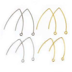 Könnte beinhalten: Eine Sammlung von Ohrring-Zubehör in Silber- und Goldtönen. Die Draht-Komponenten haben ein gebogenes Design und eine kleine Schlaufe an der Unterseite zum Anbringen von Perlen oder anderen Verzierungen. Auf weißem Hintergrund.
