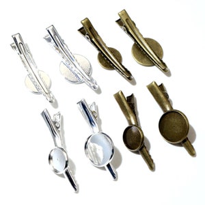 May include: A set of eight silver and bronze metal hair clips with round glass cabochons. The clips are designed for attaching to hair or fabric.