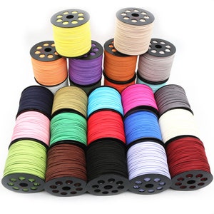 Peut inclure: Assortiment de 20 bobines de cordon en daim coloré, chacune enroulée autour d'une bobine en plastique noire avec des trous. Les cordons sont disposés en demi-cercle, les bobines étant face au spectateur.