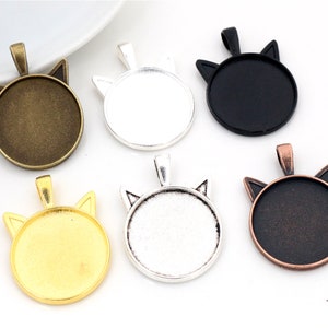 Könnte beinhalten: Sechs katzenförmige Anhänger-Tabletts in verschiedenen Metalloberflächen: Antikmessing, Silber, Schwarz, Kupfer, Gold und Weiß. Jedes Tablett hat eine runde, flache Oberfläche zum Einsetzen von Harz oder anderen Verzierungen.