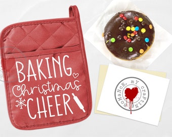 Op de afbeelding: Rode gewatteerde ovenwant met de tekst "Baking Christmas Cheer" in wit met een sneeuwvlok en een deegroller.