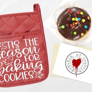 Può includere: Guanto da forno imbottito rosso con il testo "Tis the season for baking cookies" in bianco. Un omino di pan di zenzero e un albero di Natale sono inclusi nel design.