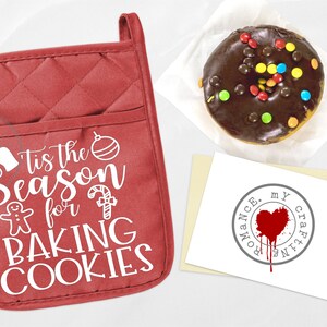 May include: Red quilted oven mitt with the text "Tis the Season for Baking Cookies" in white. The text is surrounded by a gingerbread man, a candy cane, and an ornament.