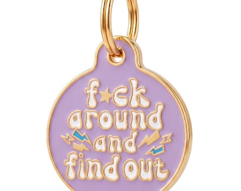 May include: A round, lavender-colored metal pet tag with a gold-toned rim and a matching gold split ring. The tag features the white text "f*ck around and find out" in a wavy font, accented by small gold and blue lightning bolt icons.